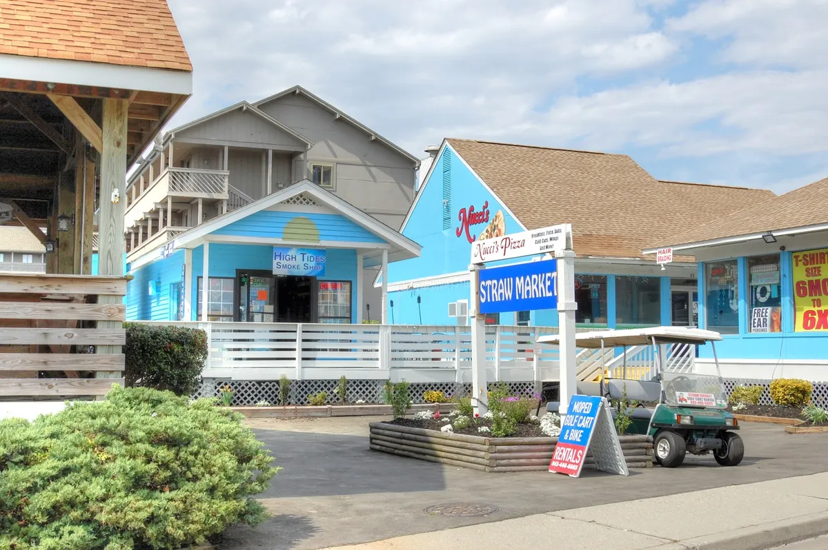 A lively exterior shot of colorful market buildings with a prominent market sign and a golf cart parked nearby. The area is bustling yet inviting, suggesting opportunities for shopping, dining, and mingling with locals and visitors alike.
